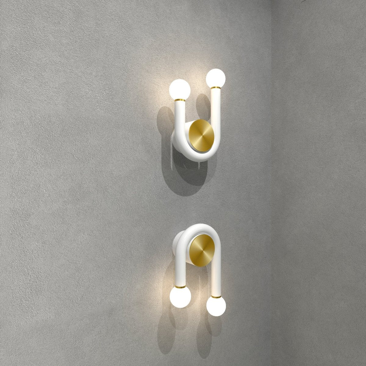 Clérachic white U-shaped wall lamps with brass discs, one upright and one inverted, lit on a textured grey concrete-effect wall.