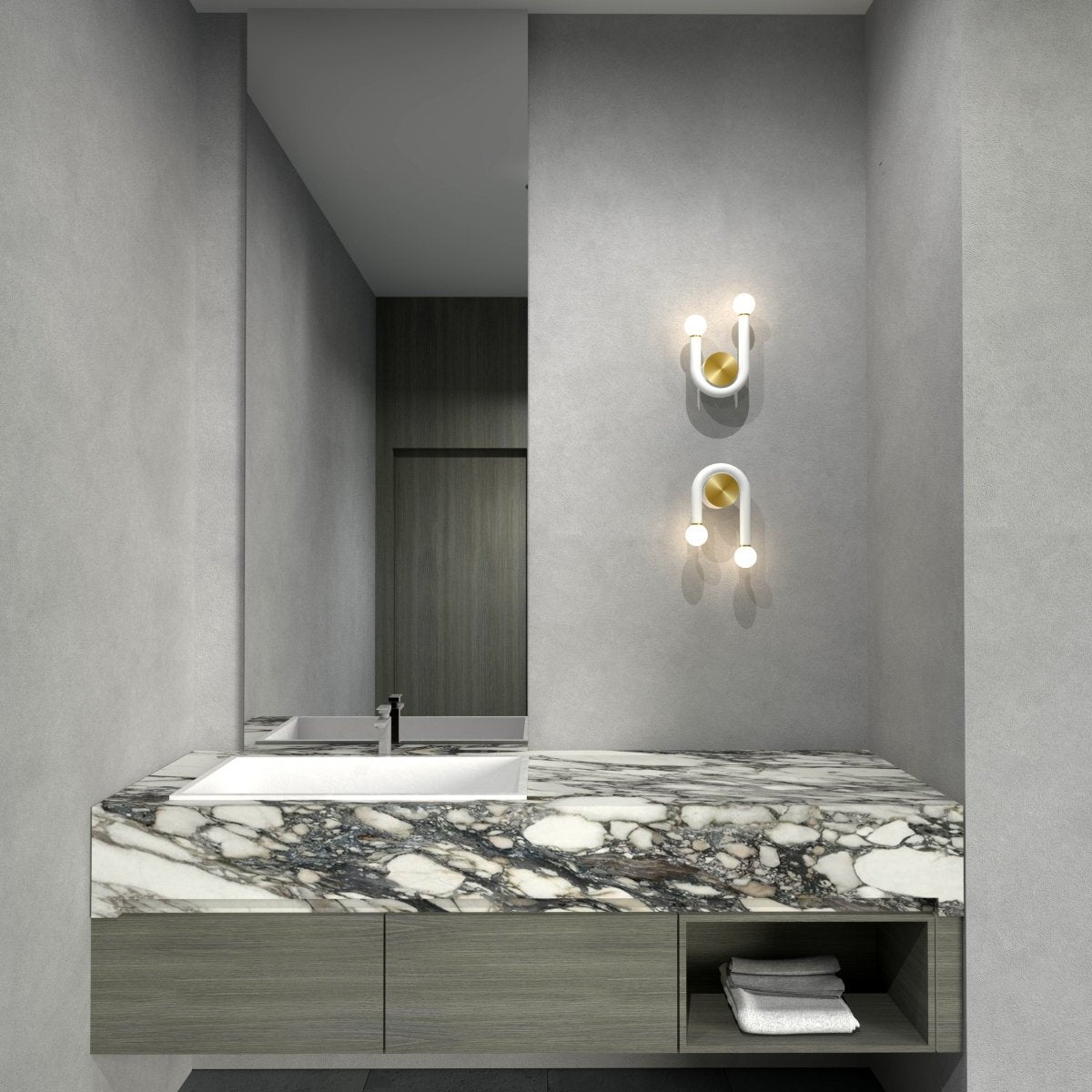 Clérachic pair of white U-shaped wall lamps with brass discs mounted above a marble vanity and mirror in a grey bathroom.