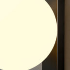 Detail of the lit globe curving past the black metal bar on this Clérachic wall light, filling most of the frame in soft cream light.