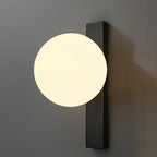 Lit globe on a vertical black bar, this Clérachic wall light is fixed to a dark grey wall and glows a warm white.