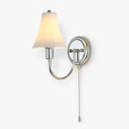 Fluted white ceramic shade on a polished chrome curved arm with a pull chain, on this Clérachic wall light against a plain white backdrop.