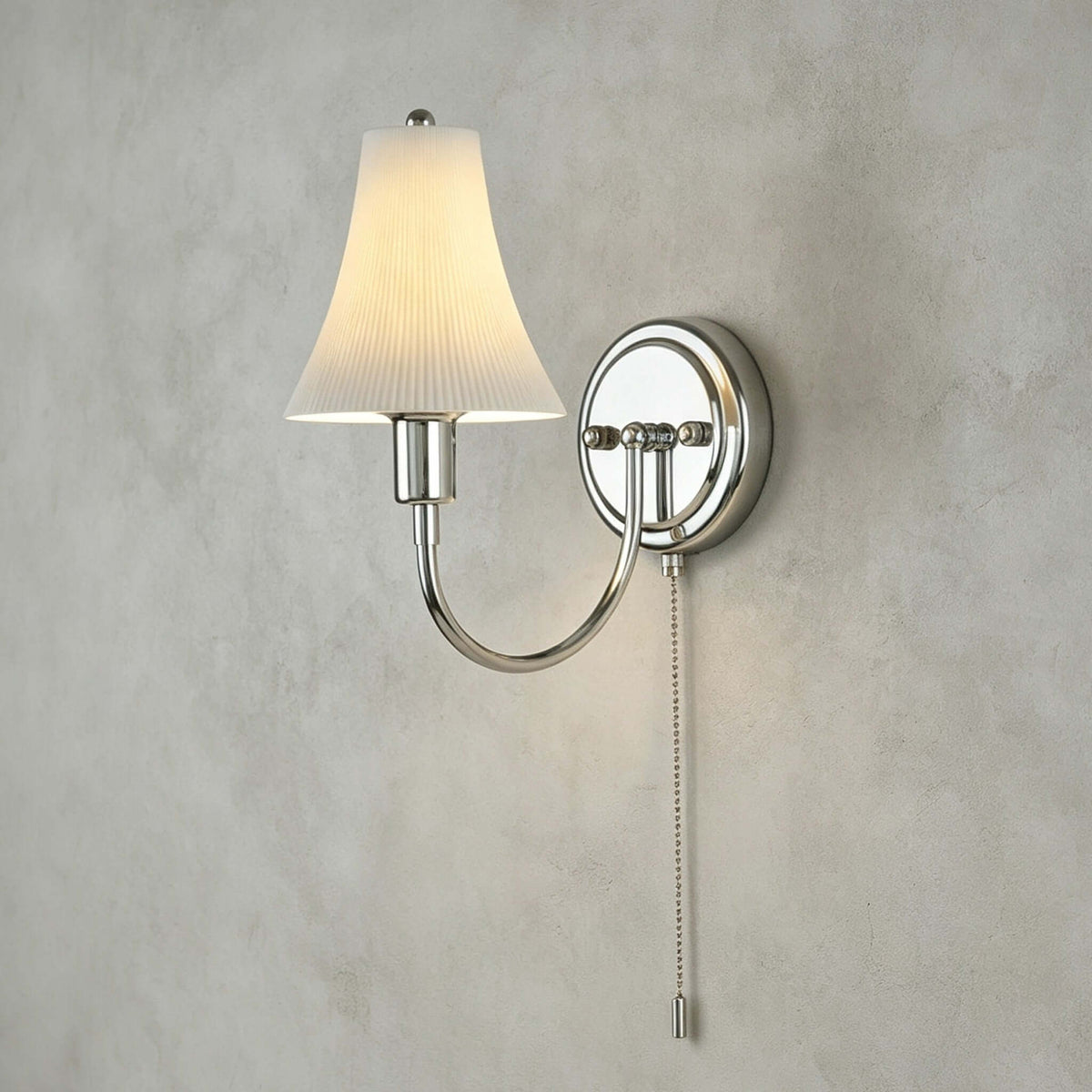 Close view of the fluted ceramic shade, round chrome backplate and beaded pull chain of this Clérachic wall light on textured grey plaster.