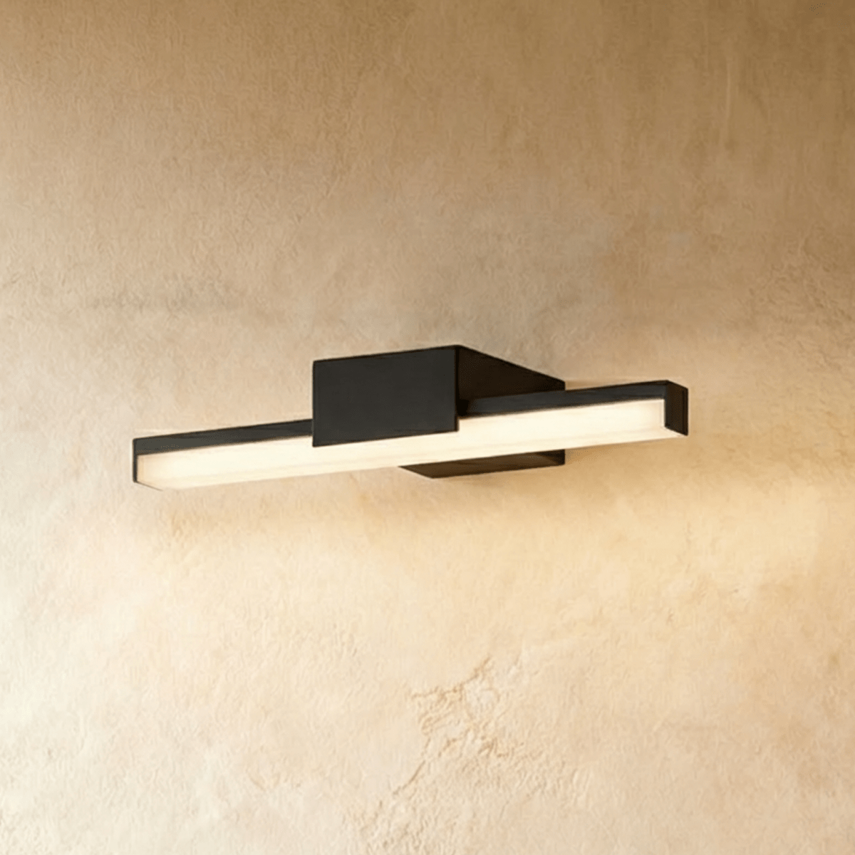 Clérachic slim black linear wall light with a square backplate, glowing warm against a textured limewash wall.
