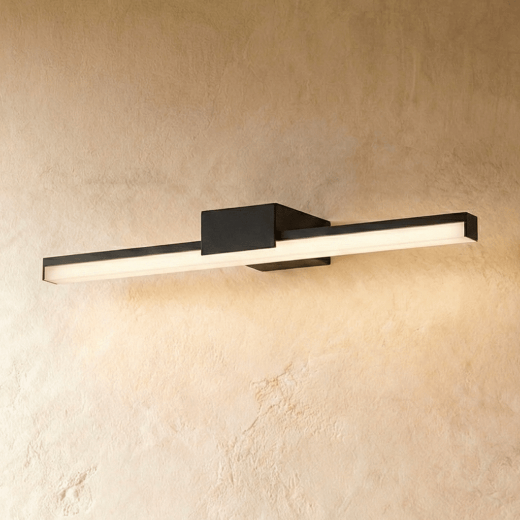 Clérachic long black linear wall light with a glowing frosted diffuser and a compact square backplate on plaster.
