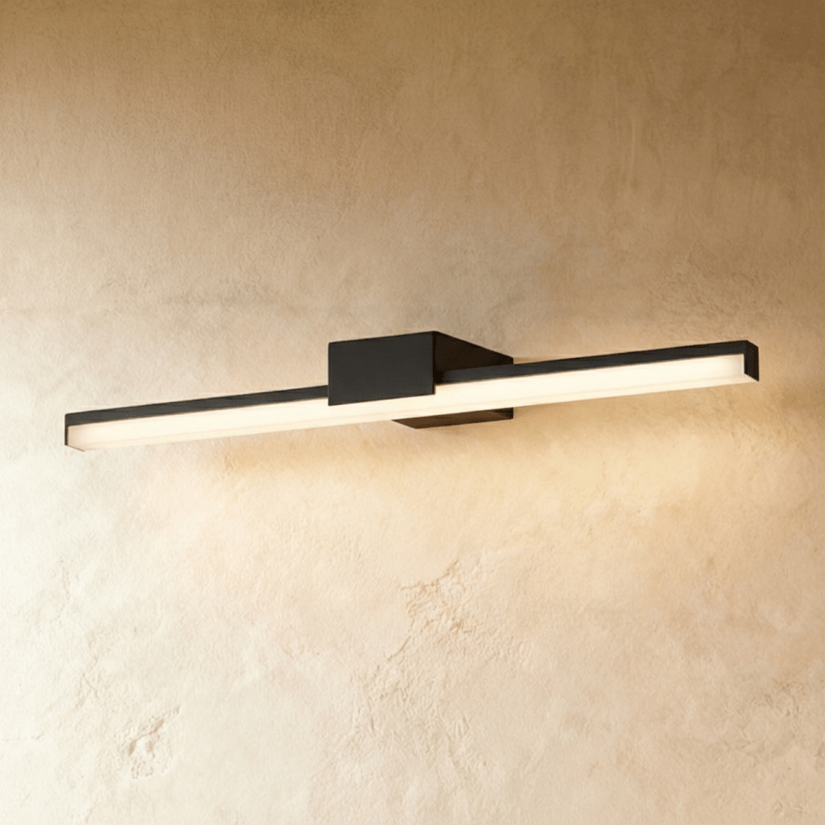 Clérachic extra-long black linear wall light casting a soft warm glow along a textured, sand-toned wall.