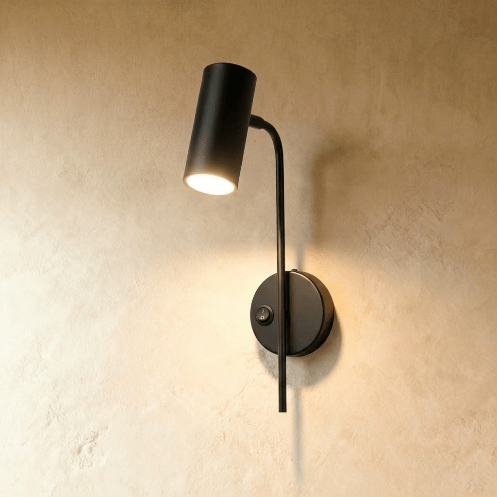 Clérachic black wall reading light with a small rocker switch on its round plate, the cylinder spot lit.