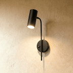Clérachic black wall reading light with a small rocker switch on its round plate, the cylinder spot lit.
