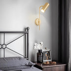 Clérachic gold wall reading light above a bedside table with a dark vase, framed print and a metal bed frame.