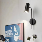 Clérachic black wall reading light on a white wall above a framed poster and a small bunch of thistles.