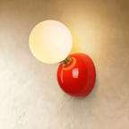 Clérachic red wall lamp with a lit frosted globe on a glossy red dome plate with a brass collar, on plaster.