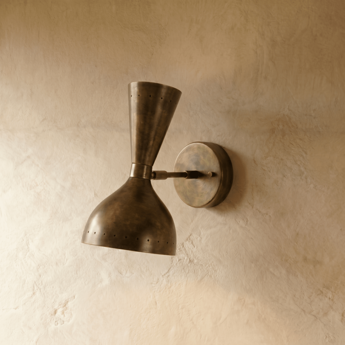 Clérachic wall lamp in vintage brass shown from another angle, pinpoints of light rimming both cones.