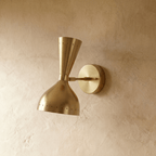 This Clérachic wall lamp in brushed brass viewed close, pinpoints of light rimming both cones.