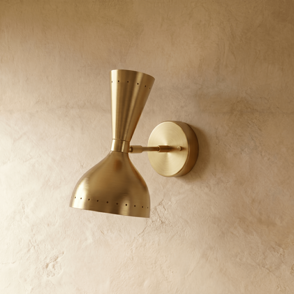 This Clérachic wall lamp in brushed brass viewed close, pinpoints of light rimming both cones.