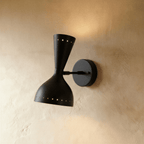 Clérachic wall lamp in matte black, an hourglass shade with perforated rims on a round wall plate.