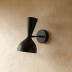 This Clérachic wall lamp in matte black viewed close, pinpoints of light rimming both cones.