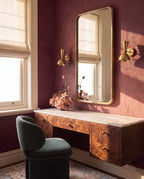 Clérachic wall lamp in brushed brass, a pair flanking a mirror above a burl-wood vanity desk.