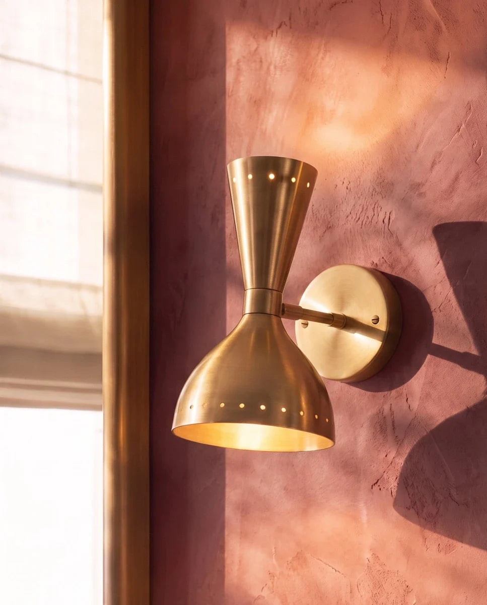 Clérachic wall lamp in brushed brass shown close beside a window on a warm terracotta plaster wall.