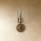 Clérachic brass wall light switched off, showing the ribbed clear glass shade, candle-style bulb and stepped round backplate.