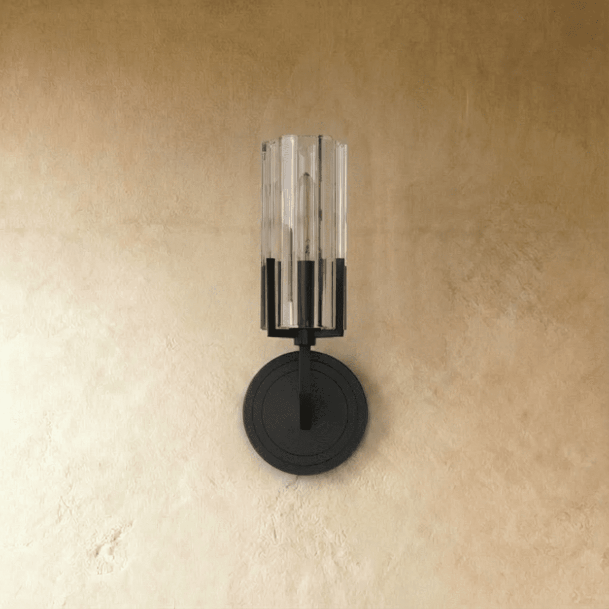 Clérachic black metal wall light with a ribbed clear glass shade, unlit, on a round stepped backplate against textured plaster.