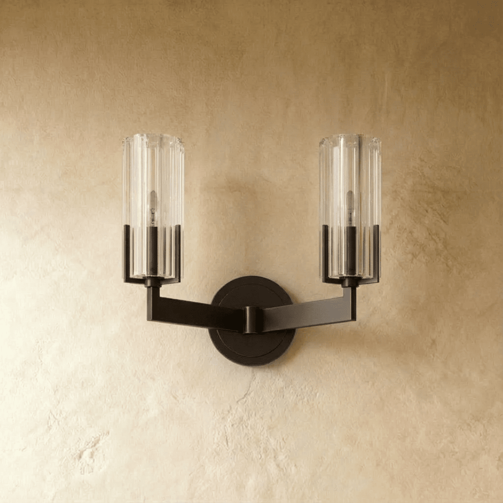 Clérachic twin-arm black wall light switched off, with two ribbed glass cylinders and a matching round backplate on plaster.