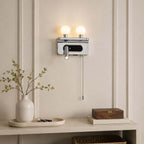 This Clérachic wall light in chrome, with two glowing globes and a reading spotlight, hangs above a console with a vase of twigs.