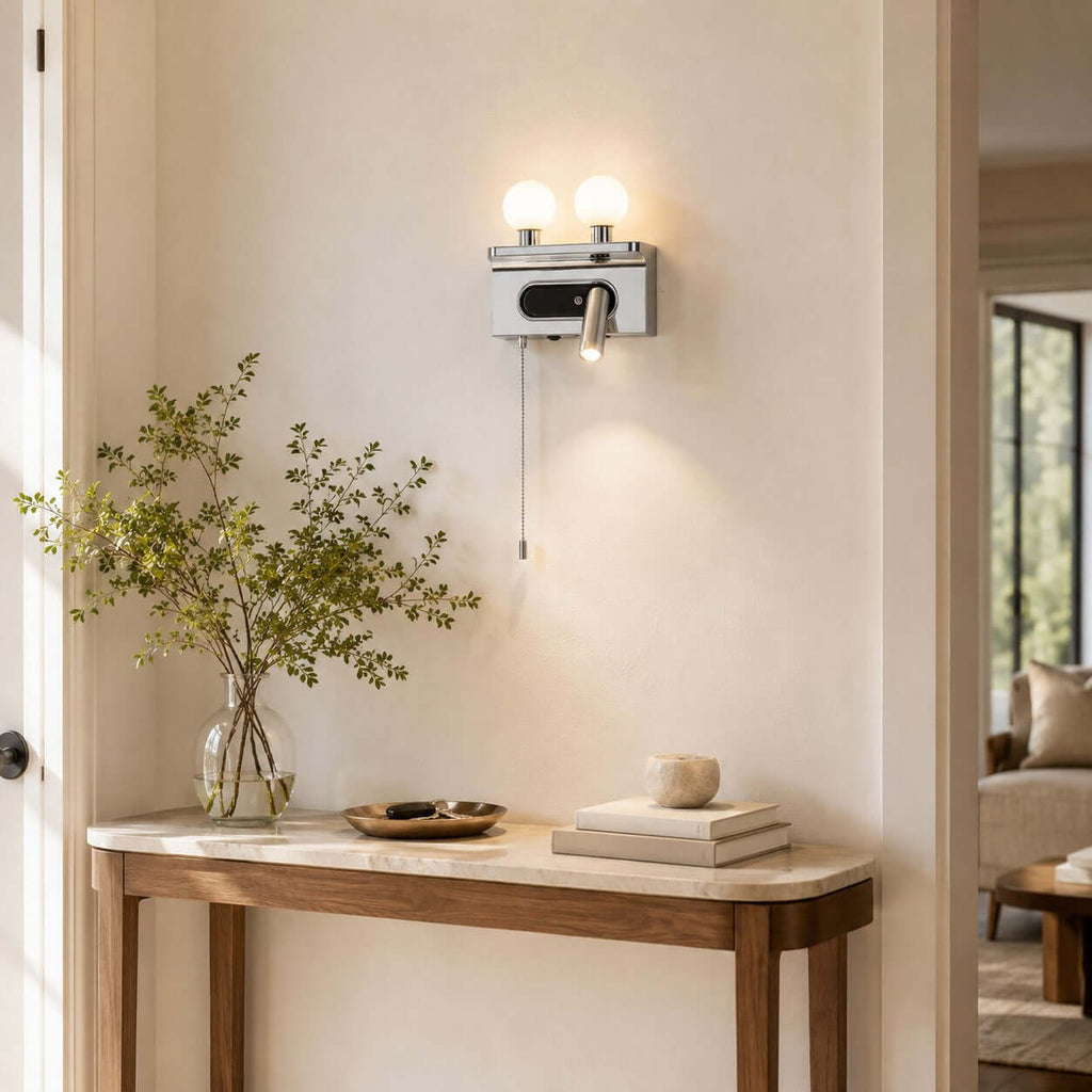 This chrome Clérachic wall light, with two globes and a spotlight, hangs in a doorway above a slim console with a vase.