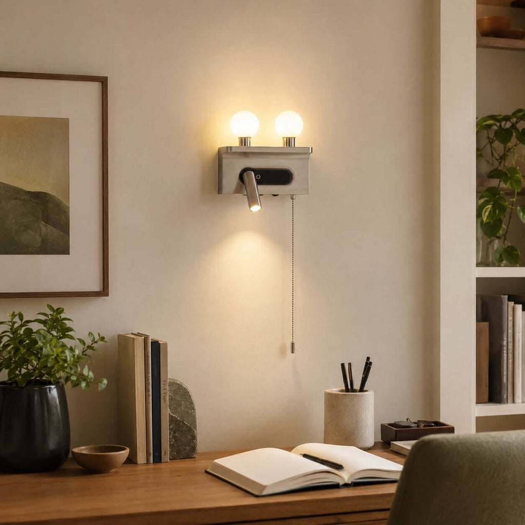 Nickel Clérachic wall light with a downward spotlight, mounted above a desk with an open notebook and a pen pot.