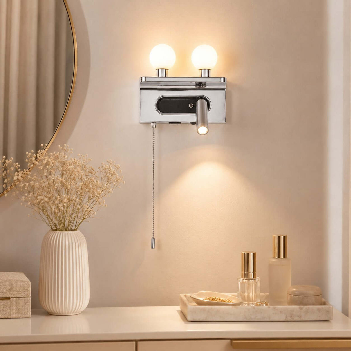 A chrome Clérachic wall light glows above a dressing table with perfume bottles and dried grasses in a ribbed vase.
