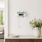 A chrome Clérachic wall light with unlit white globes hangs above a marble-topped sideboard with a vase of flowers.