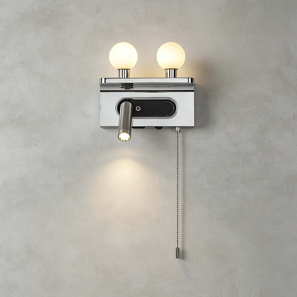 Close view of the chrome Clérachic wall light on a grey wall, with two lit globes, a spotlight and a beaded pull chain.