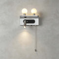 Close view of the chrome Clérachic wall light on a grey wall, with two lit globes, a spotlight and a beaded pull chain.