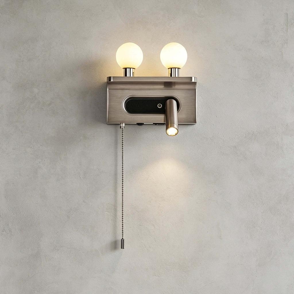 This Clérachic wall light in nickel shows two lit globes, a reading spotlight and a long chain pull on a grey wall.