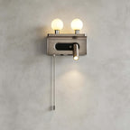 This Clérachic wall light in nickel shows two lit globes, a reading spotlight and a long chain pull on a grey wall.