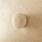 Clérachic round opal glass dome wall light, switched off, sitting flush on a limewashed plaster wall.