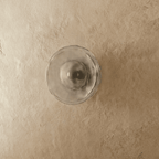 Clérachic flush wall light with a clear rippled glass disc and a dark bulb at its centre, switched off on plaster.