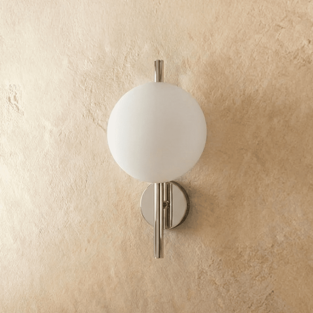 Clérachic wall light with a frosted white glass globe on a polished chrome rod, switched off against plaster.