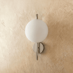 Clérachic wall light with a frosted white glass globe on a polished chrome rod, switched off against plaster.