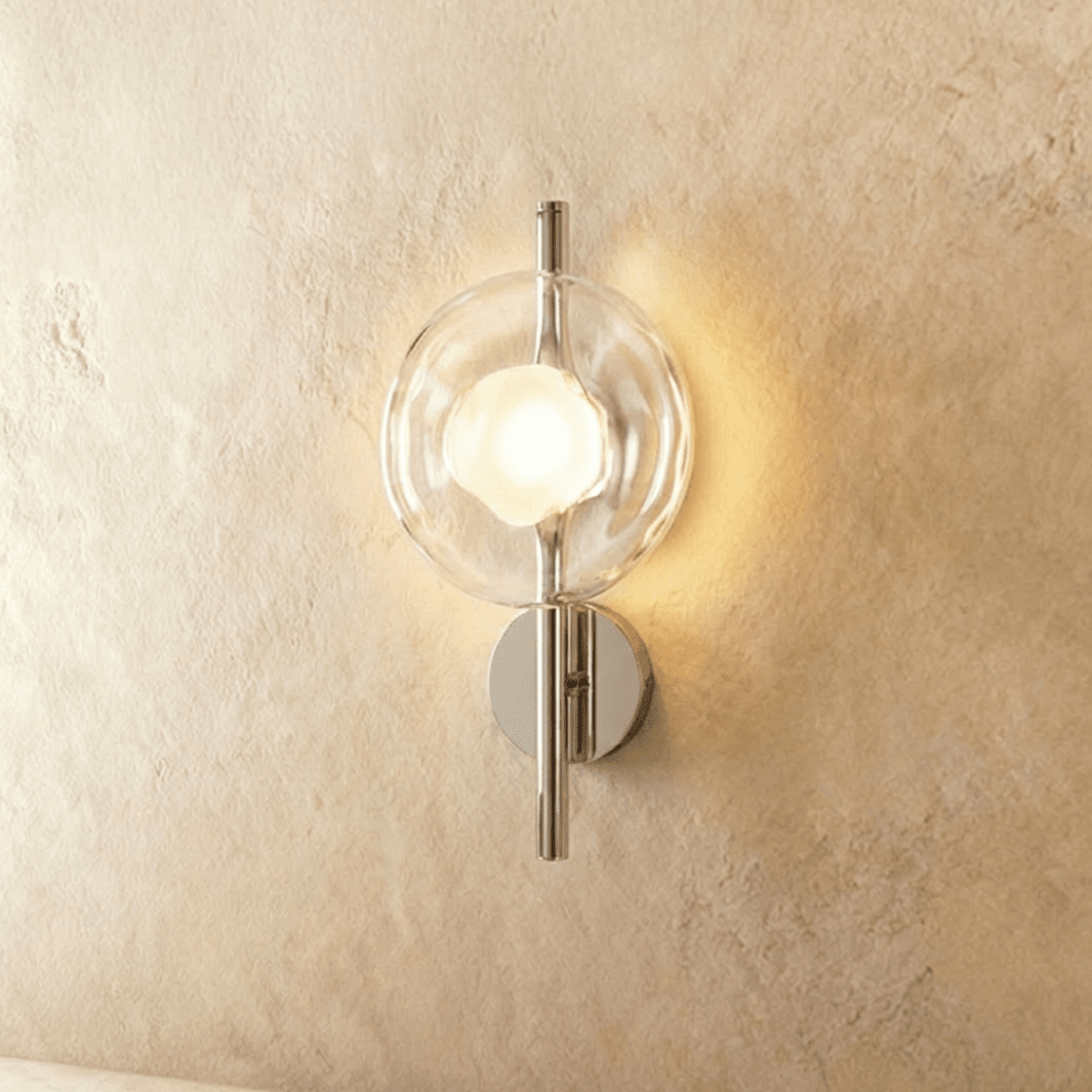 Clérachic wall light with a clear rippled glass disc and frosted bulb glowing on a polished chrome rod.