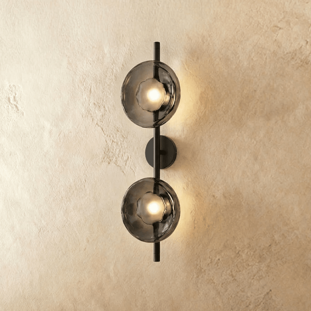 Clérachic two-shade wall light with smoky grey glass discs glowing warm on a slim black vertical rod and round backplate.