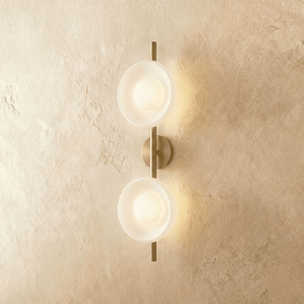 Clérachic two-shade wall light with frosted white glass dishes glowing soft on a brushed gold vertical rod and round backplate.