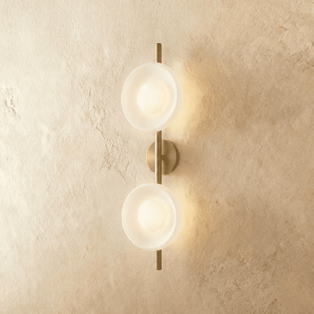 Clérachic two-shade wall light with frosted white glass dishes glowing soft on a brushed gold vertical rod and round backplate.