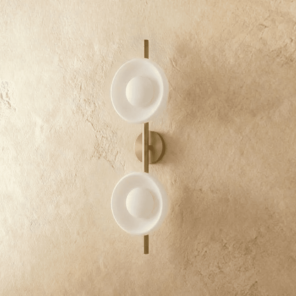 Clérachic two-shade wall light with white glass dishes and opal globes on a brushed gold rod, switched off on plaster.