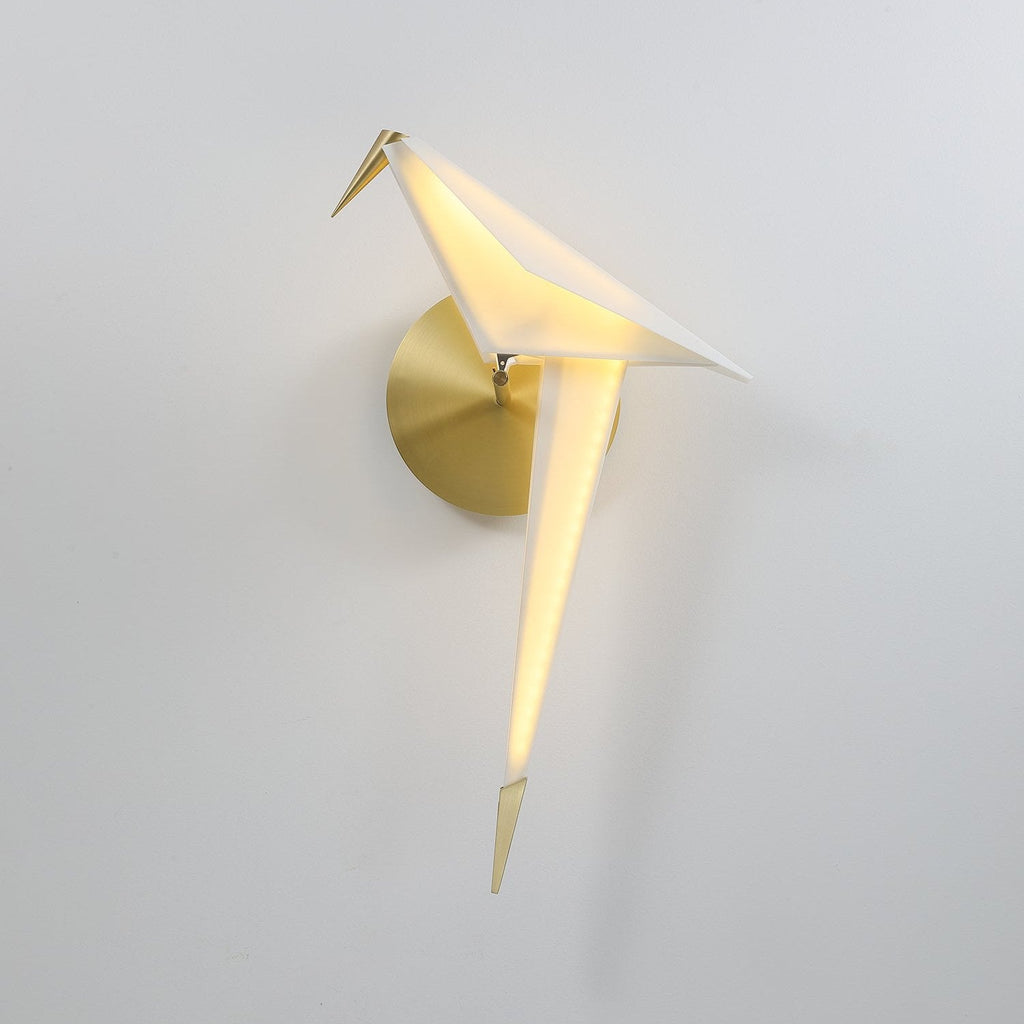 This Clérachic bird wall light tilts its head forward on a pale wall, the light glowing along its white tail to a gold point.