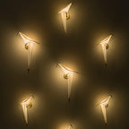 Six Clérachic bird wall lights glow on a dark wall, each lit warm and spaced out in a loose pattern.