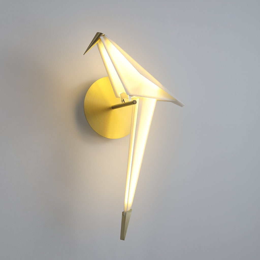 The same Clérachic bird wall light, lit more brightly, with a clear glow along the tail and the head tilted slightly down.