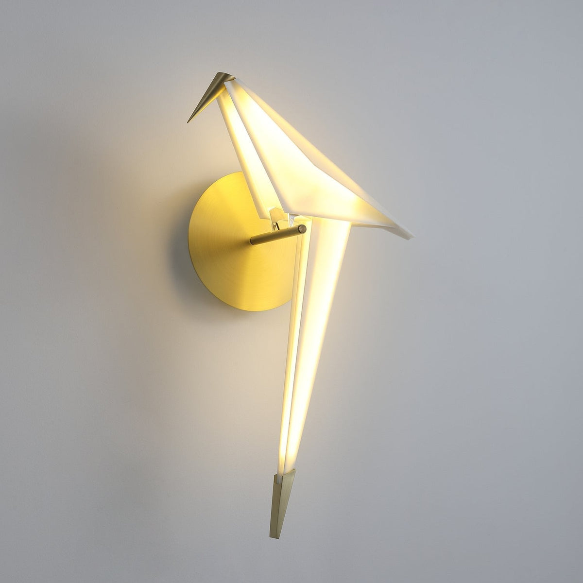 The same Clérachic bird wall light, lit more brightly, with a clear glow along the tail and the head tilted slightly down.