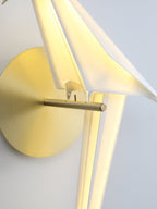 Close view of the gold perch and backplate on a Clérachic bird wall light, with the lit white body behind them.