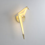 Seen from the side, this lit Clérachic bird wall light glows from its white back and tail, with a gold beak on a pale wall.