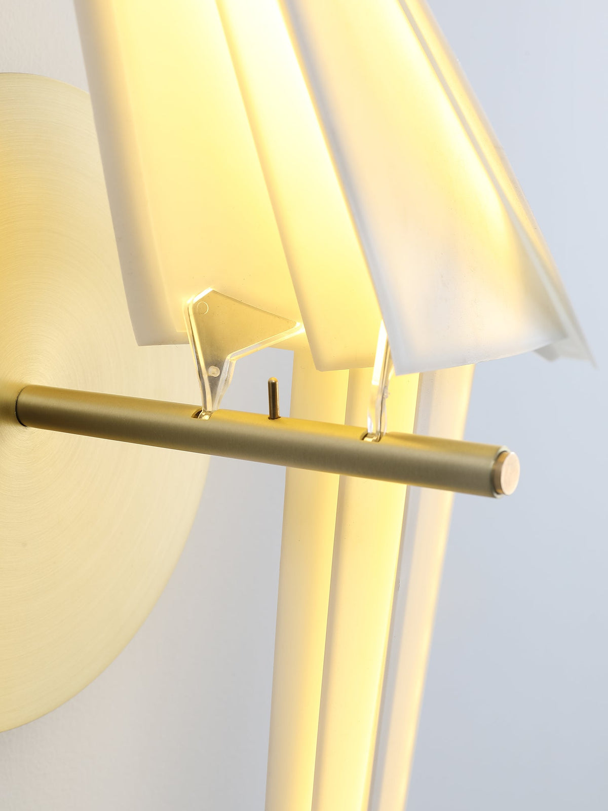 Close view of the gold perch bar and the clear fixings holding the folded white body of this Clérachic bird wall light.