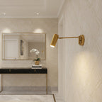 Clérachic gold wall light lit beside a framed mirror, above a black console table with white orchids.